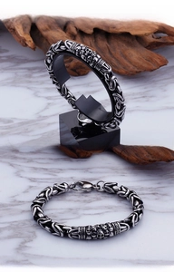 Detail of punk titanium steel bracelet featuring skull relief and woven chain links