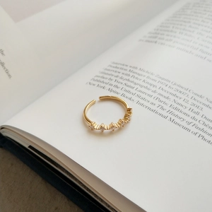 Dettaglio di un anello d'oro regolabile con cinque zirconi su un libro