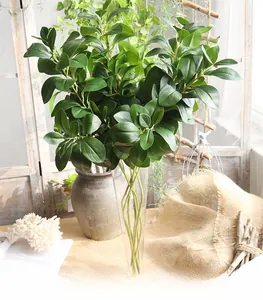 Detail of artificial Milanese leaf greenery in a slim glass vase with natural home decor