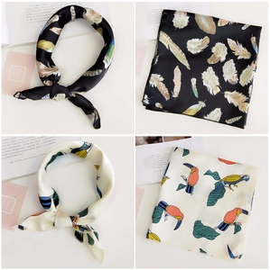 Detail view of printed silk scarves featuring feather and tropical toucan patterns