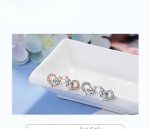 Detail view of heart-shaped zircon earrings in rose gold and silver on white ceramic