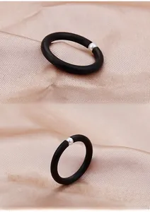 Macro detail of minimalist matte black ring with a single white pearl on silk fabric