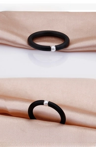 Detail view of a matte black ring featuring a single silver bead accent on a satin base