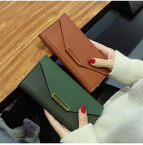 Detailed view of long envelope wallets in brown and green litchi grain leather texture