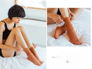 Detail of orange cable knit slouch socks with ruffled edges in a cozy home setting