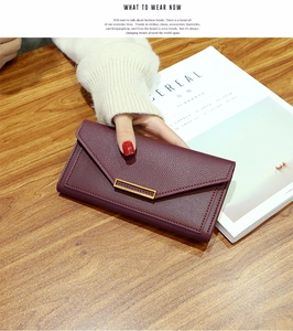 Detail of burgundy long wallet with lychee pattern leather and gold metal buckle