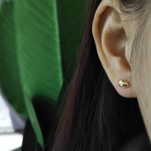Minimalist 925 sterling silver golden teardrop stud earrings worn by a model