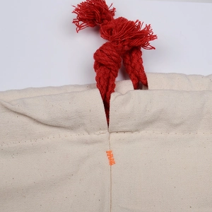 Close-up of canvas drawstring bag showing fabric texture, red rope, and orange stitching