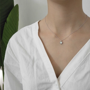 Close-up of minimalist s925 silver necklace with opal pendant worn by a model