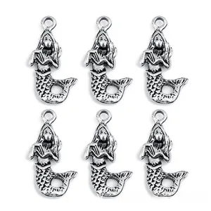 Detailed close-up of vintage silver mermaid tail charms for DIY jewelry making
