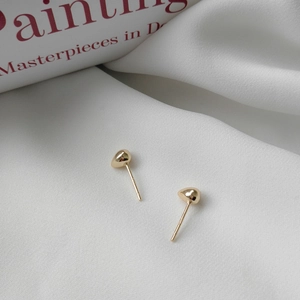 Detail of S925 sterling silver stamp on minimalist gold heart-shaped stud earrings