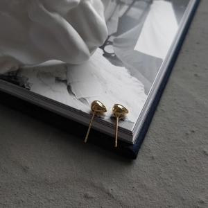 Close-up of gold-plated 925 sterling silver teardrop earrings on minimalist background