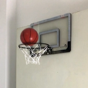 Actiefoto van een mini-basketbal die in de zwarte ring gaat met een transparant bord