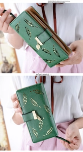 Detail of dark green leather wallet featuring hollow leaf design and metal pendant