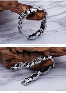 Detailed view of silver stainless steel Cuban chain bracelet with skull and cross relief