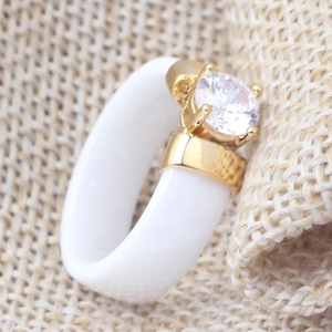 Macro view of a 6mm white ceramic ring with a gold setting and a clear zircon stone