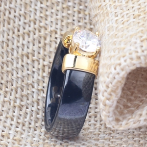 Macro shot of a 6mm black ceramic ring featuring a gold claw-set white cubic zirconia stone