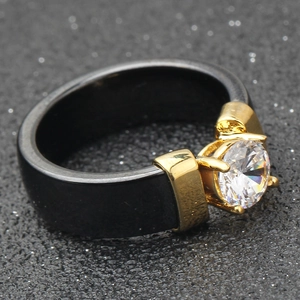 Close-up of a 6mm black ceramic ring with a round zircon stone in a gold prong setting