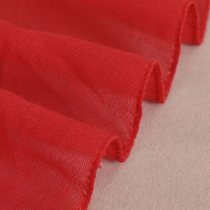 Close-up of bright red lace fringe scarf showing delicate woven texture and soft fabric detail