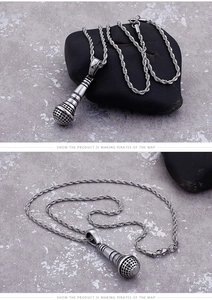 Detailed view of a silver microphone pendant with a twisted chain on stone surface