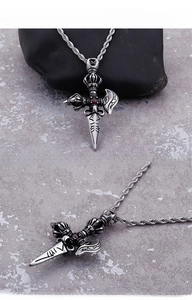 Macro detail of vintage titanium steel vajra pendant with red ruby inlay and braided chain