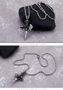 Detail of vintage titanium steel vajra cross pendant with red gem and twisted chain