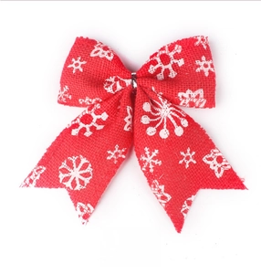 Detail of red burlap Christmas bow with white snowflake pattern and woven texture
