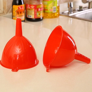 Set of two red plastic kitchen funnels with long handles on a marble countertop