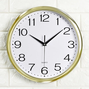 Classic 12 inch golden wall clock with white dial and black Arabic numerals on a brick wall