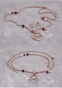 Makroaufnahme des rotgoldenen Infinity-Schmucksets mit dekorativen Perlen