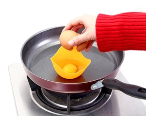 Close-up of cracking an egg into a yellow silicone egg poacher in a frying pan