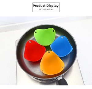 Set of four colorful heart-shaped silicone egg poachers placed in a pan for boiling