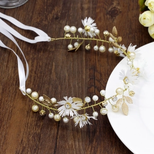 Detail of floral bridal headband with white pearls and gold leaves on ceramic plate