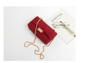 Close-up of red chevron jelly bag with matte texture, golden lock and chain strap detail