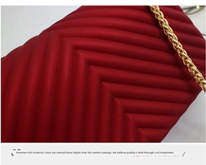 Close-up of red PVC fabric with V-shaped quilting and golden metal chain detail