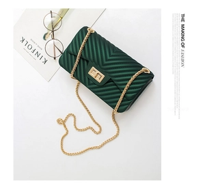 Detailed close-up of dark green V-pattern quilted mini bag with golden metal chain