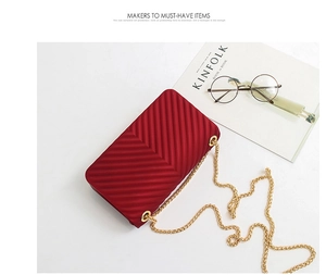 Flat lay of red V-quilted mini chain bag with matte finish and gold shoulder strap