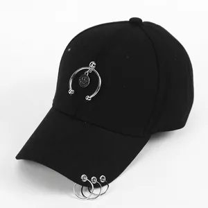Detail of black cotton baseball cap featuring silver rings on brim and smiley pendant