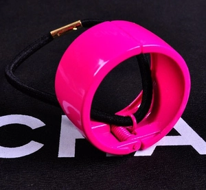 Detail view of a rose pink ponytail cuff with black elastic tie and gold metal clasp