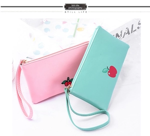 Flat lay of pink cherry and mint apple PU leather wristlet pouches with metal zippers