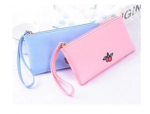 Detailed view of light blue and pink cartoon pouches with cherry and strawberry embroidery