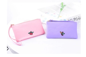 Detail showing two PU leather pouches with cherry and banana embroidery in pink and purple