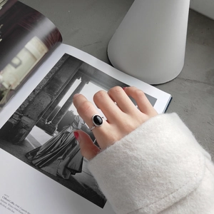 Macro view of minimalist 925 silver ring featuring oval black onyx on a model's hand