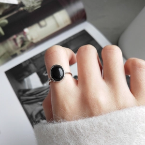 Detailed close-up of a minimalist 925 silver ring featuring an oval black onyx gemstone