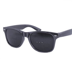Detail of black foldable pinhole glasses showing hinge structure and three-hole lens design