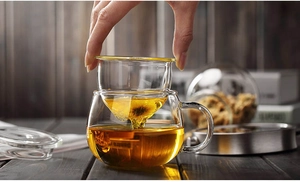 Detail of lifting tea infuser from borosilicate glass cup with a blooming flower tea