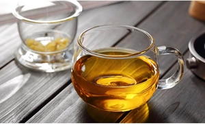 Close-up of thick borosilicate glass tea cups with lids on a dark wooden table surface