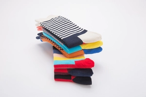 Detail of stacked colorful striped cotton crew socks with vibrant patchwork patterns