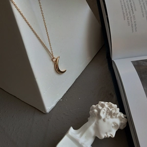 Minimalist 925 sterling silver moon pendant necklace in gold on a geometric stand