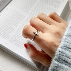 Detailed view of vintage S925 sterling silver cross ring worn against a book background